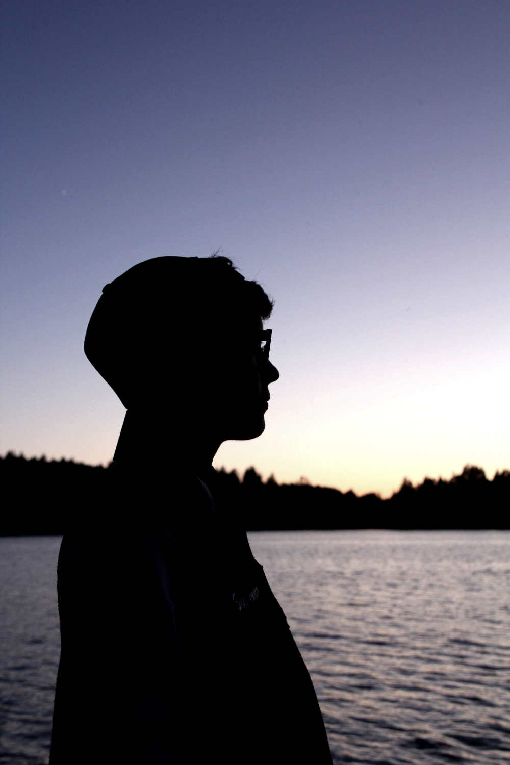 A person looking out at the water during sunset.